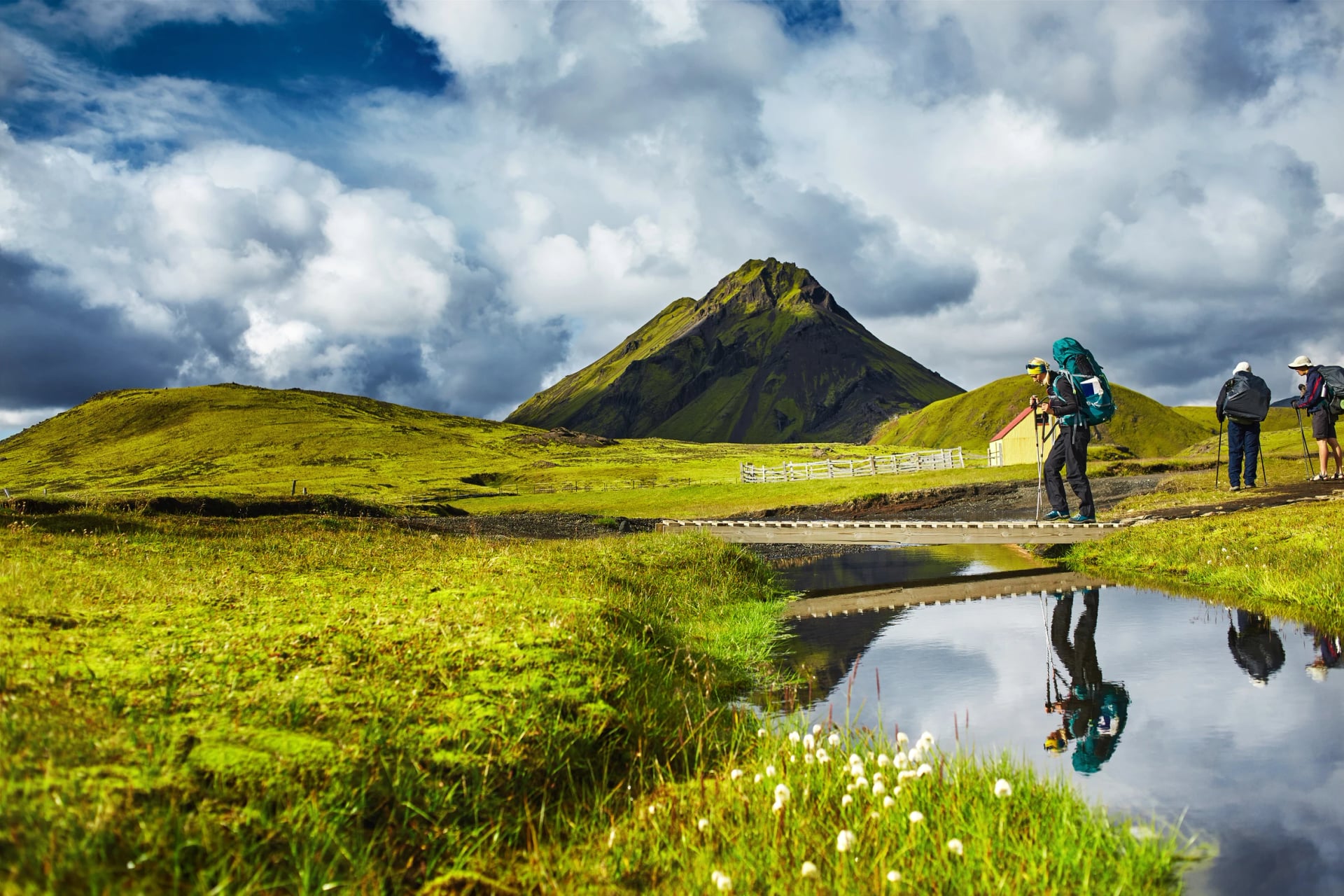 Voyage en Islande. Magnifique paysage islandais avec un randonneur traversant un ruisseau, des montagnes, le ciel et des nuages. Randonnée dans le parc national de Landmannalaugar