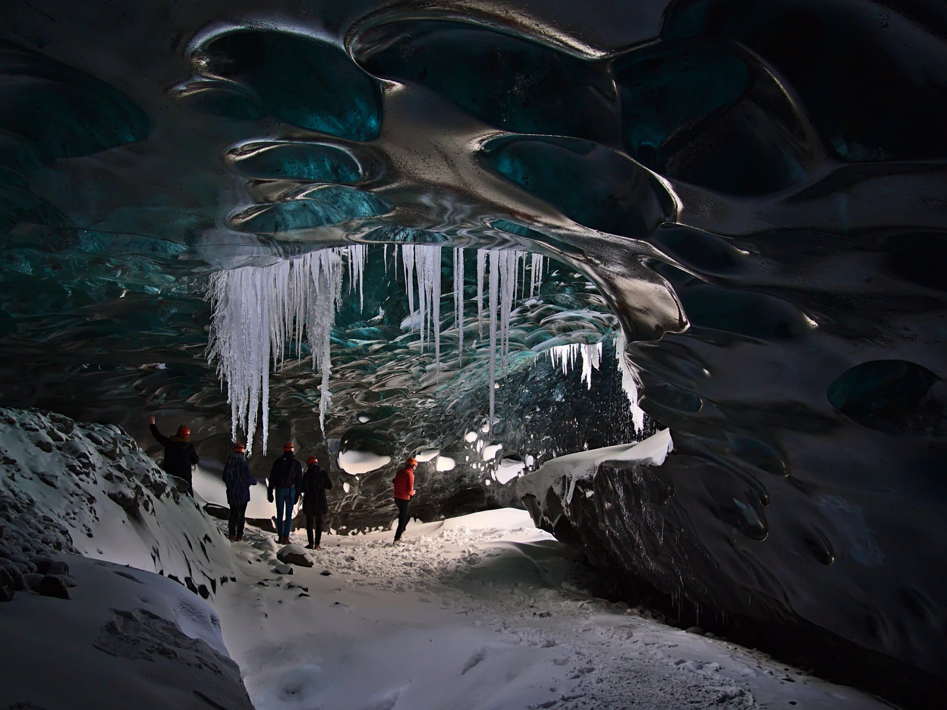 Groupe de touristes explorant la grotte de glace saphir, située dans le glacier de Breiðamerkurjökull, Vatnajökull, Islande, lors d'une visite avec un trou de moulin dans le plafond bleu scintillant et des stalactites suspendues.