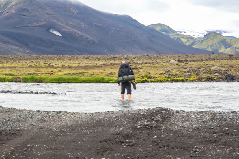 Adventurers crossing a river while hiking in the volcanic landscapes of Iceland