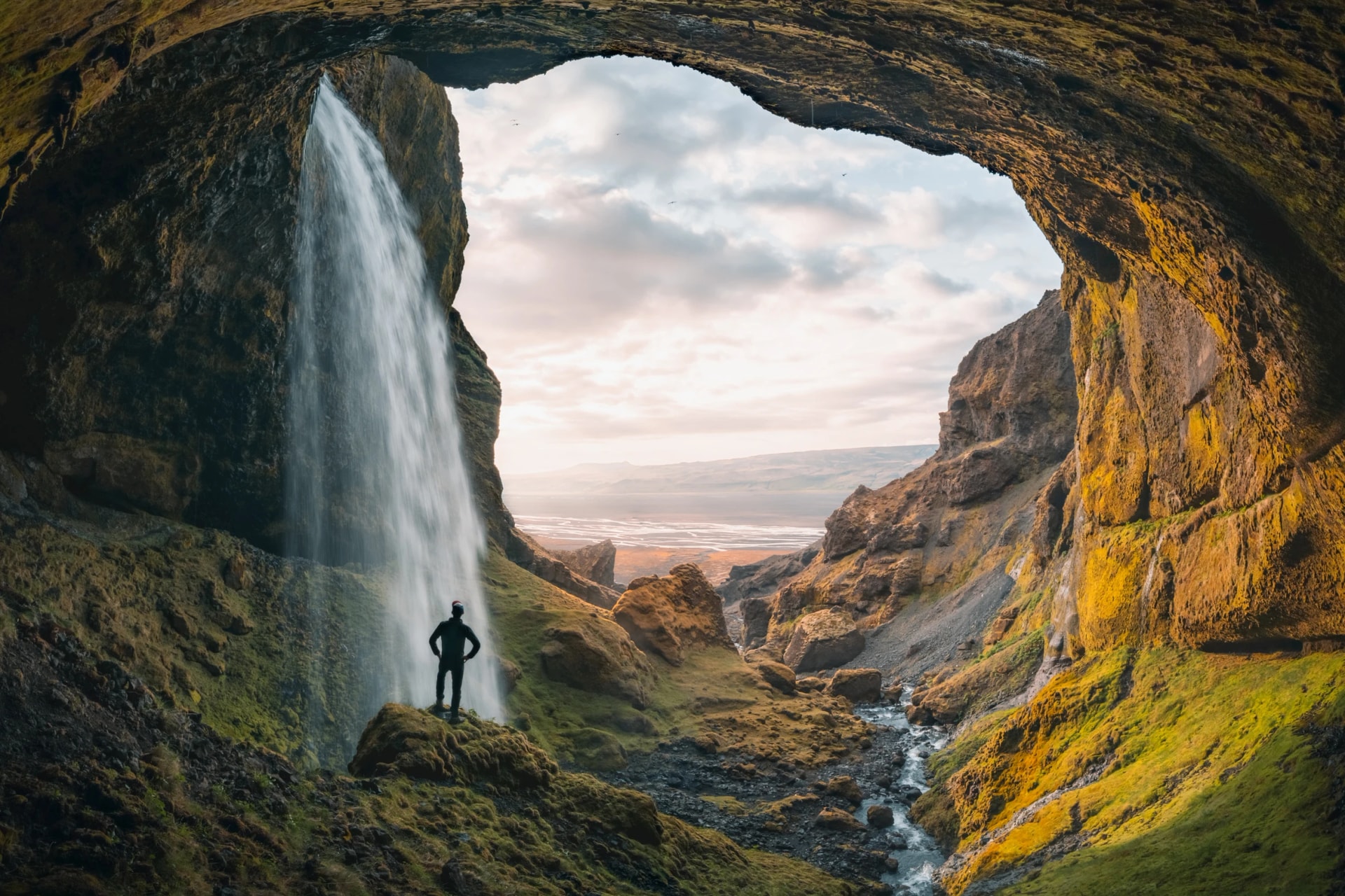 Adventurous young man standing behind waterfall in the highlands of Iceland. High quality panorama photo. High quality photo