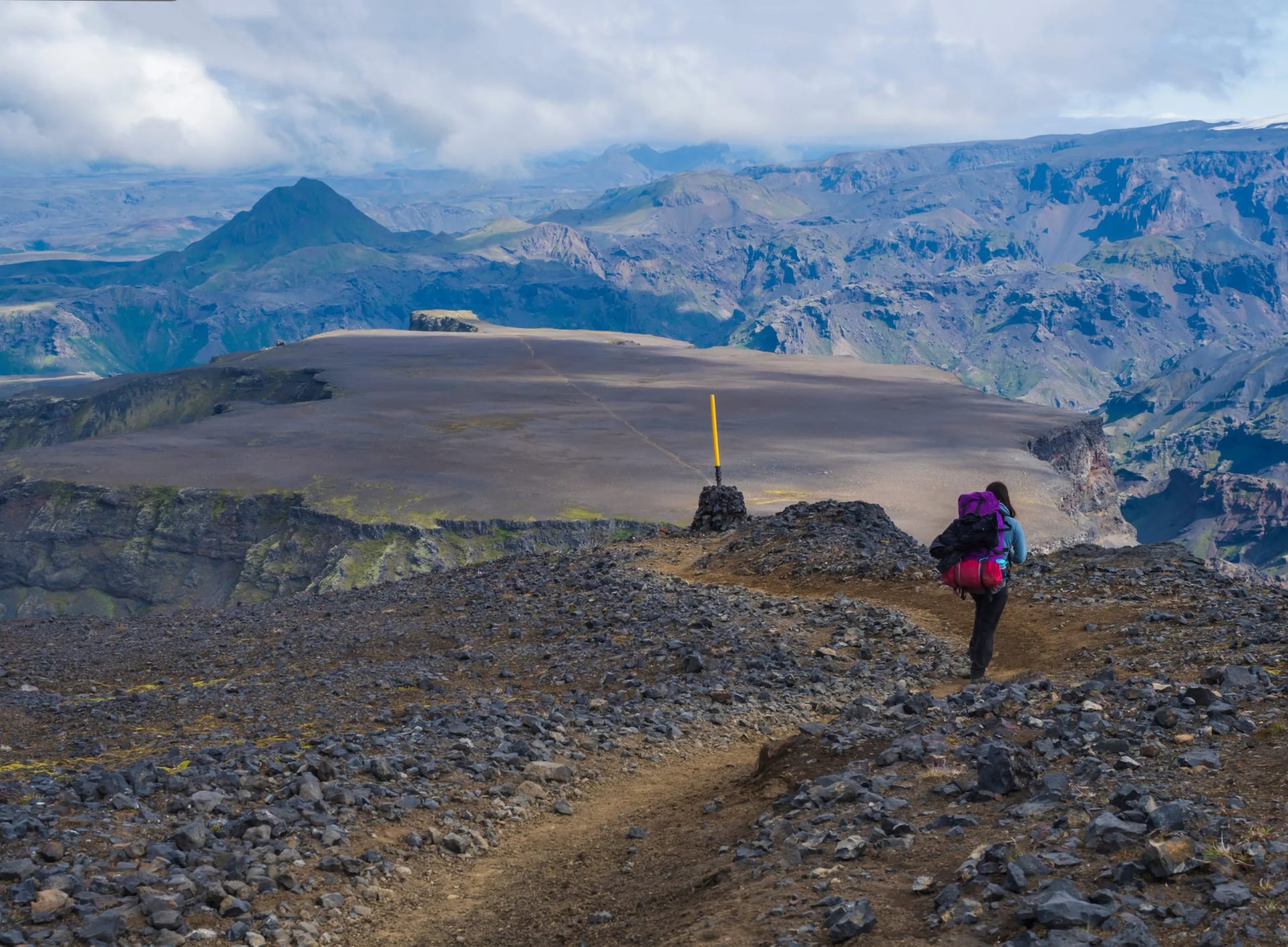 Ung kvinde vandrer med rygsæk ved Fimmvörðuháls vandresti. Landskab af Gudernes land med ujævne grønne mosdækkede klipper og bakker, dalen af thorsmork, Island, Sommer blå himmel hvide skyer